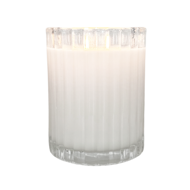 A tall, clear glass candle holder with a white, creamy-looking candle inside.