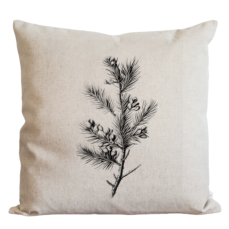 a black and white pillow with a pine branch on it