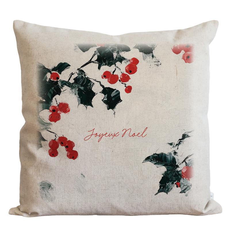 A white pillow with a design of red berries and green leaves, along with the text "Joyeux Noel" printed on it.