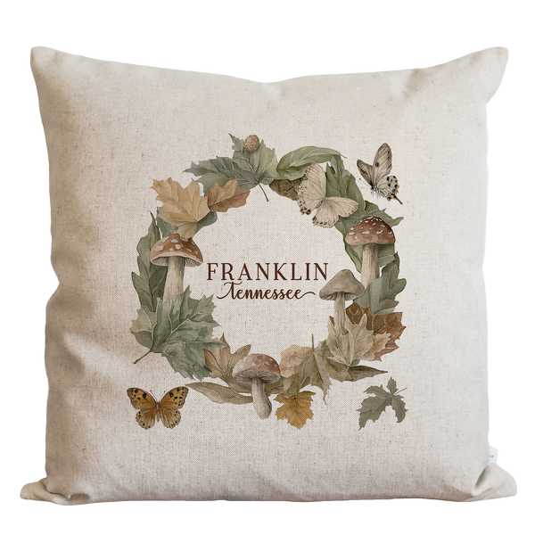 A beige pillow with a wreath design featuring autumn leaves, mushrooms, and butterflies. The text "FRANKLIN Tennessee" is displayed in the center of the wreath.