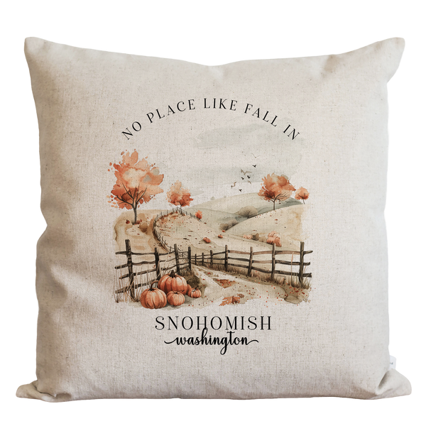A beige pillow with a printed image of a rural landscape, featuring a wooden fence, trees with orange leaves, and pumpkins. The text "NO PLACE LIKE FALL IN SNOHOMISH washington" is printed below the image.