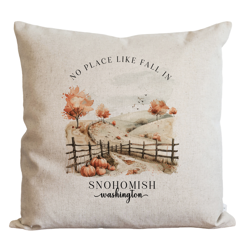 A beige pillow with a printed image of a rural landscape, featuring a wooden fence, trees with orange leaves, and pumpkins. The text "NO PLACE LIKE FALL IN SNOHOMISH washington" is printed below the image.