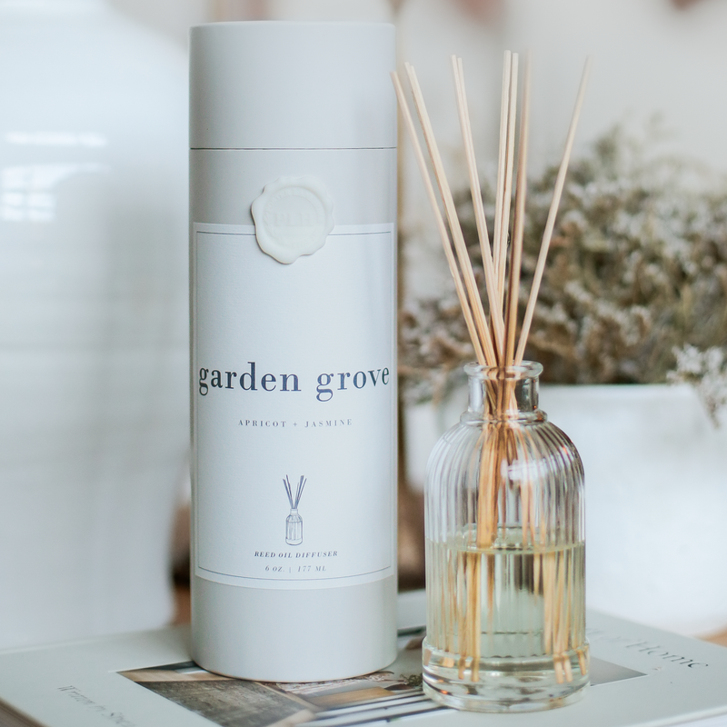 a bottle of reeds sitting on a table next to a candle