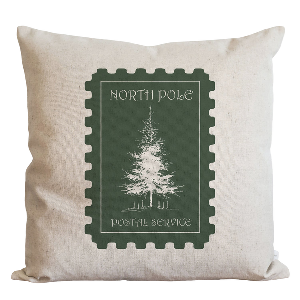 A white pillow with a green postage stamp design featuring a tree on it.