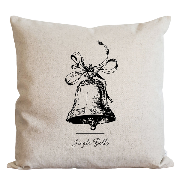 A beige pillow with a black and white illustration of a bell and the text "Jingle Bells" below it.