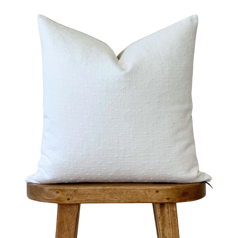 a white pillow sitting on top of a wooden chair