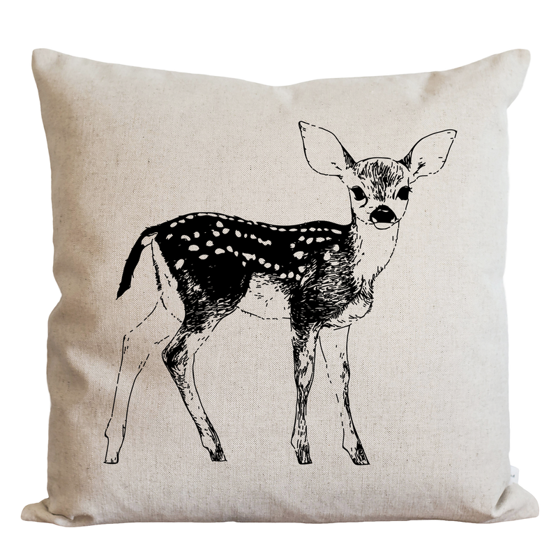A beige pillow with a black and white illustration of a deer standing upright.
