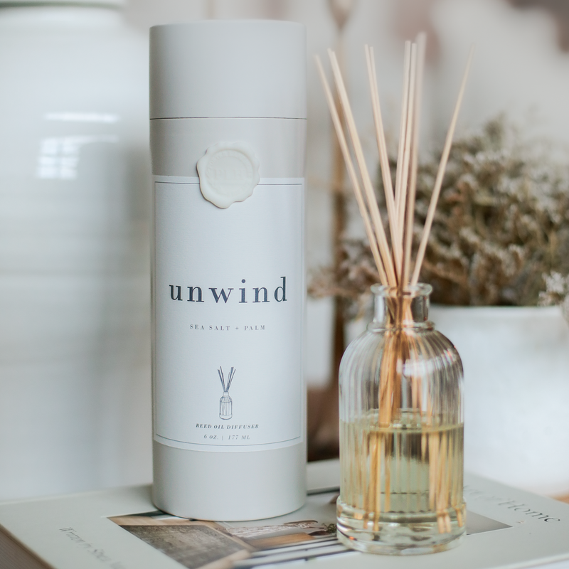 a bottle of unwind next to a reed diffuser