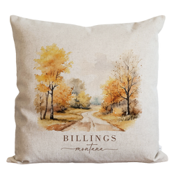 a pillow with a watercolor painting of a country road