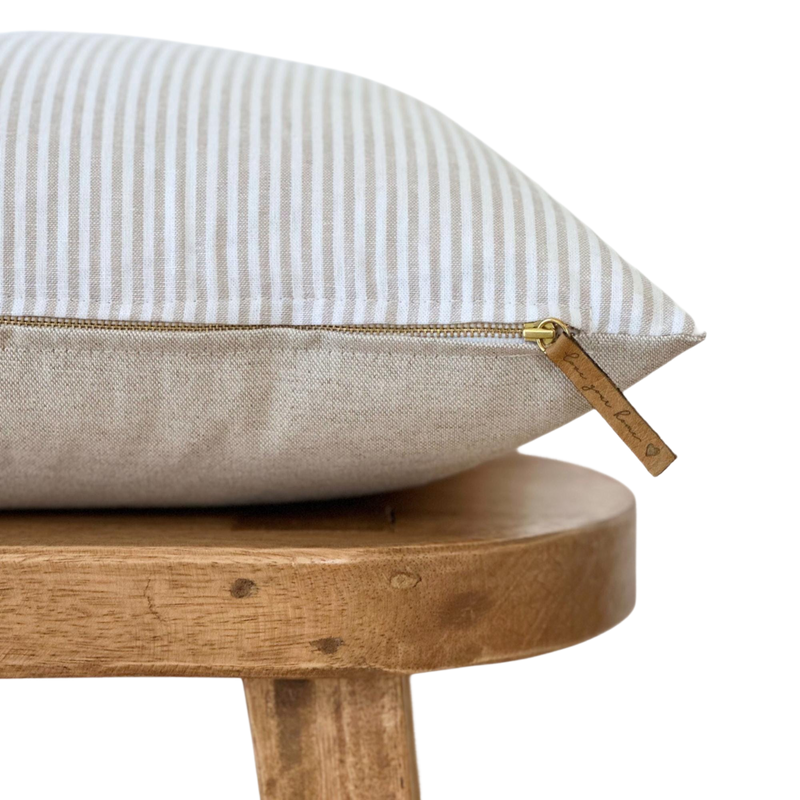a white and blue striped pillow on a wooden stool