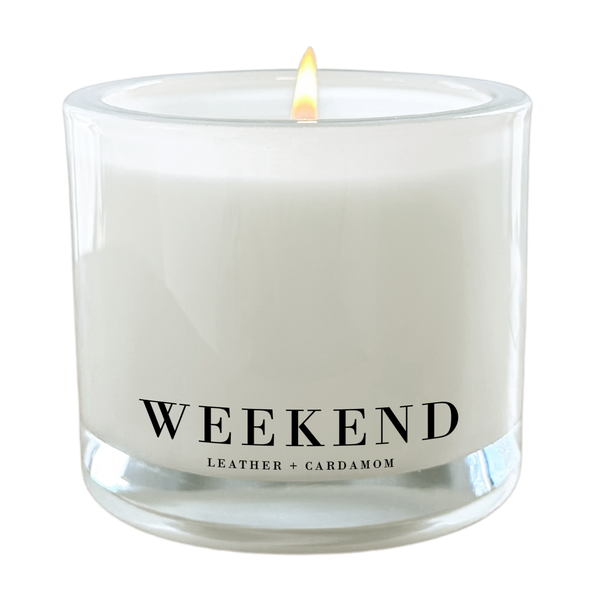 A white candle with a lit flame, labeled as a "Weekend" candle.