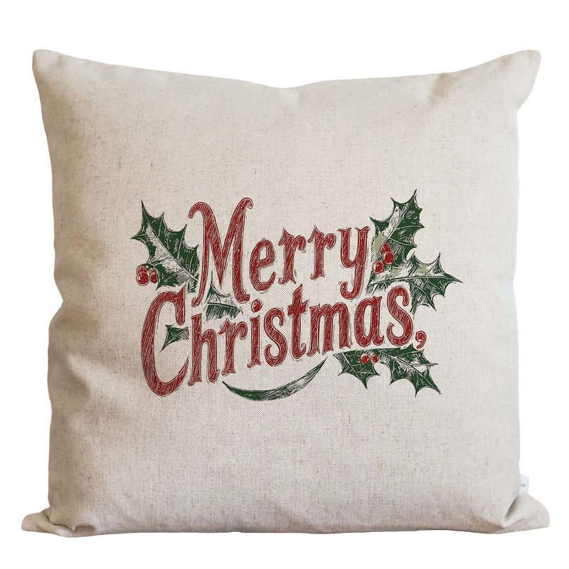 A beige pillow with the text "Merry Christmas" printed on it, surrounded by holly leaves and berries.