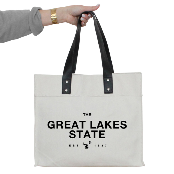 a person holding a white tote bag that says the great lakes state
