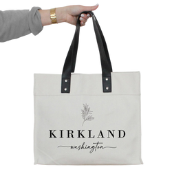 a woman's hand holding a white tote bag