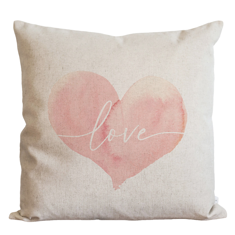 a pink heart pillow with the word love painted on it