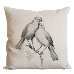 two birds sitting on a branch on a pillow