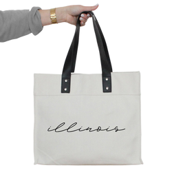 a person holding a white tote bag with the word louis on it