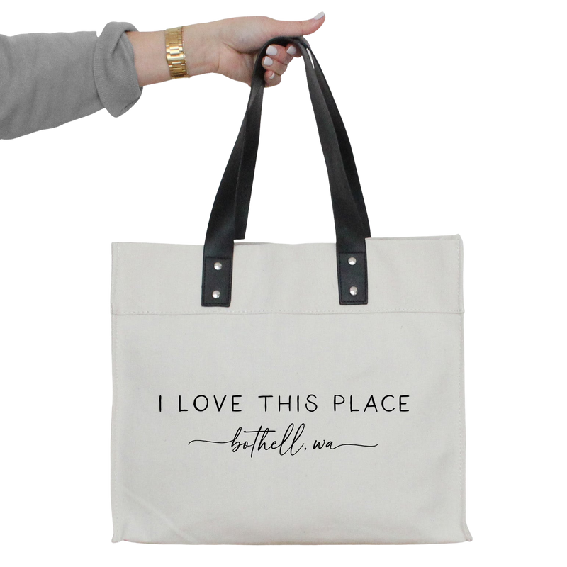a woman's hand holding a tote bag that says i love this place