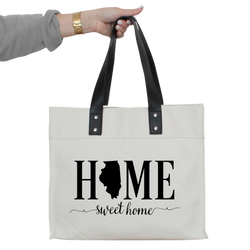 a woman's hand holding a white tote bag with the words home sweet