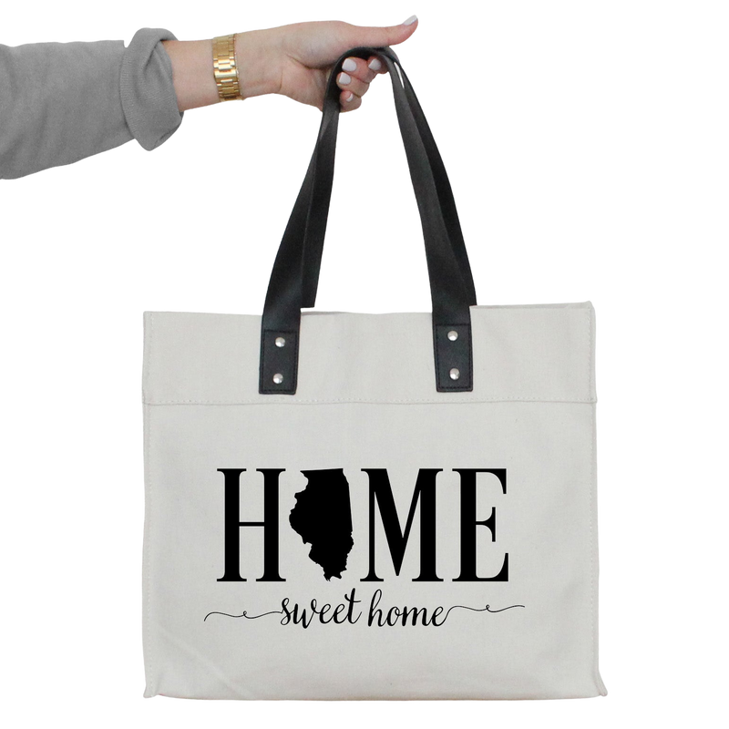 a woman's hand holding a white tote bag with the words home sweet